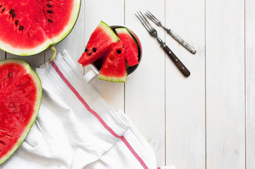 Half and slices of watermelon on a light rustic wooden background top view.