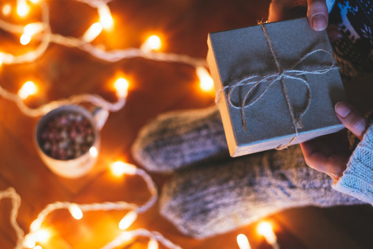 Person holding rustic paper present next to Christmas lights