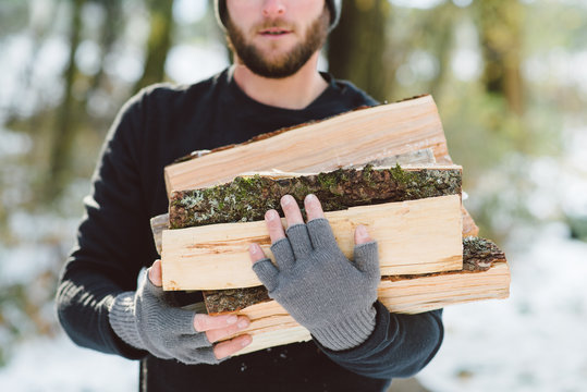 Close up shot of a pile of freshly chopped firewood held by a man.