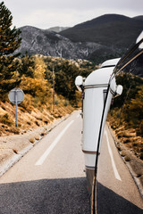 View out of a bus with a caravan trailer on a road in the Provence France with mountains in the background