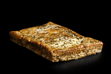 Single block of marinated tofu with herbs  isolated on black.