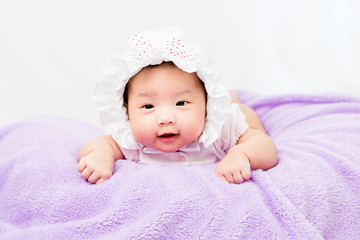 Portrait of a little adorable infant baby girl lying on the tummy on the pillow with head band