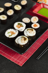 Sushi rolls on black plates and red mat