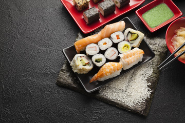 Sushi set on red and black dishes and black table background