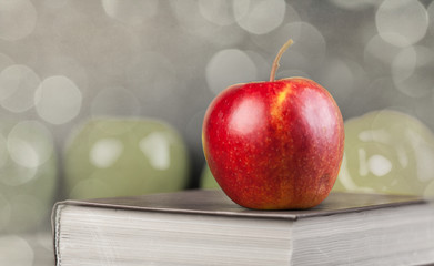 Red apple and book on a table.