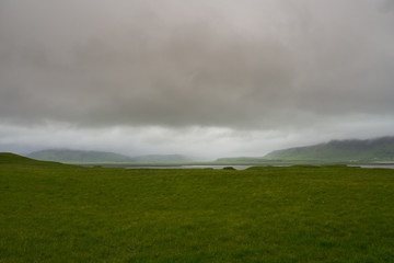 Iceland - Rain over green fields and mountains at the south coast