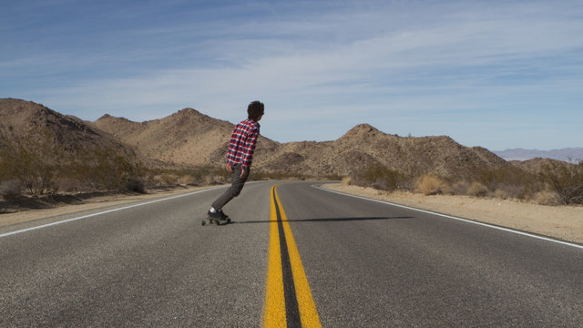 Man Skateboards Down Desert Road