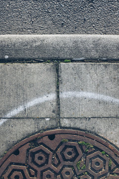 Sewer Cap And White Painted Line On Urban Sidewalk, Close Up