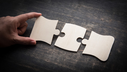 Hand holding jigsaw puzzles on a rustic wooden,wooden puzzle.