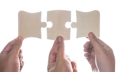 Hand holding jigsaw puzzles isolated over white,wooden puzzle.