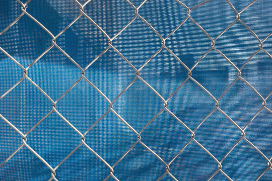Chain-link fence in front of blue plastic tarp at construction site