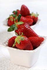 Fresh strawberries in the small ceramic bowls on the white table