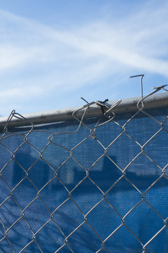 Chain-link fence in front of blue plastic tarp at construction site
