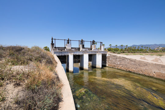 ancient open sluices in waterway river, next to Gurugu Beach in Castellon, Valencia, Spain, Europe. Blue clear sky
