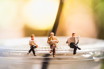 Reading, relaxing, hobby concept. Close up of Group of businessman miniature mini figure sitting...