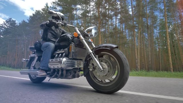 A man riding a motorcycle with its front wheel in close view. 4K.