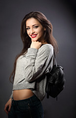 Sexy makeup woman with long hair posing with black fashion backpack on the shoulder and looking sexy on dark background