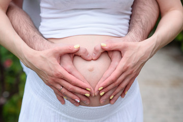 Hands on the stomach of a pregnant girl.