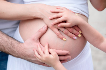 Fototapeta na wymiar Hands on the stomach of a pregnant girl.