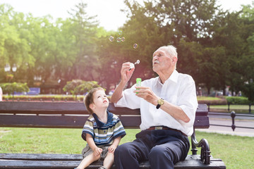 grandfather blowing soap bubbles to his grandchild