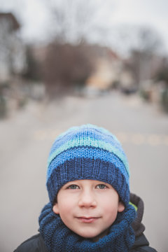 Portrait of a young boy looking at camera with a blurred street in the background
