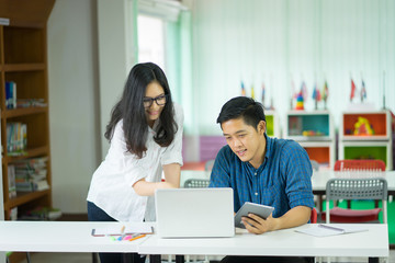 Obraz premium Young creative managers team working with new startup project in modern office. Contemporary notebook on wood table,Teamwork,brainstorming concept.talking and smiling during the conference in office