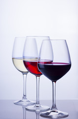 Row of three wine glasses with red, white and rose wine