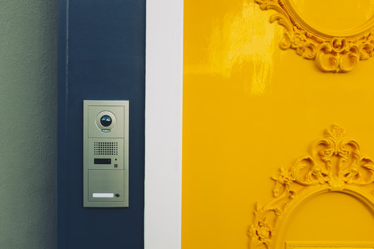 Ornate yellow door and intercom doorbell outside entrance of home