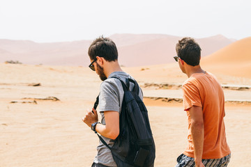 Two young men walking through the desert on adventure travel