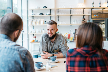Young man sittting at the cafe with friends