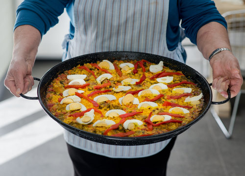 Mature spanish lady holding a home made paella