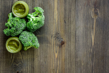 Fototapeta na wymiar Broccoli puree for baby on dark wooden table background top view copyspace