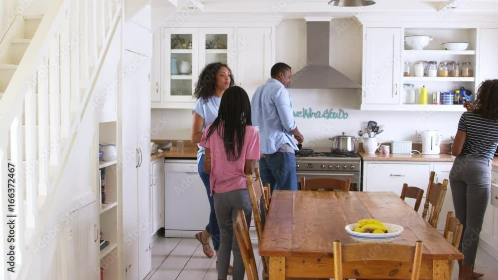 Wall mural family with teenage children laying table for meal in kitchen