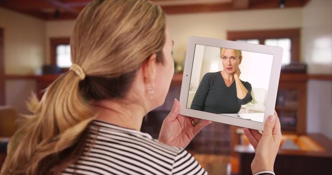 Woman having video chat with woman on tablet inside living room