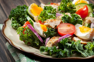 Fresh salad with chicken, tomatoes, eggs and lettuce on plate