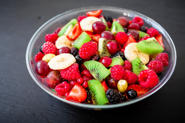 Bowl of tasty fresh fruit salad with banana, kiwi and berries