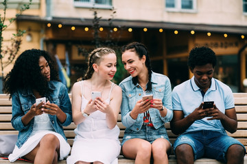 Series photo of group multiethnic hipster teenagers friends looking in smart phones while sitting...