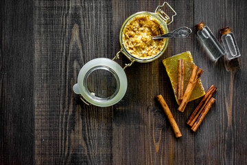 Homemade organic scrub in glass jar and soap with orange and cinnamon on dark wooden background top view copyspace
