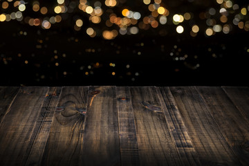 rustic wooden table top with blurred lights in black background