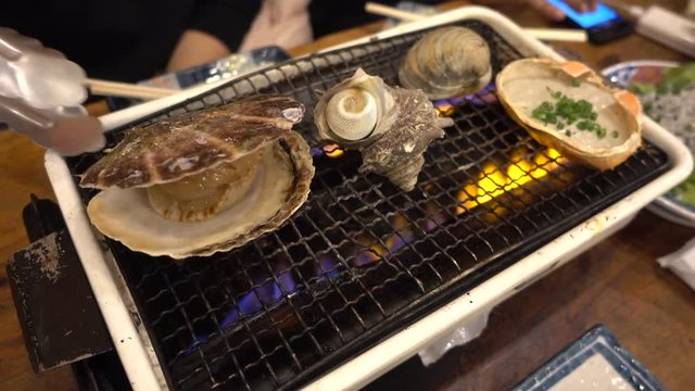 Japanese seafood barbecue , sea shell and clam shell BBQ grilled on fire from butane gas stove ,very sweet and delicious