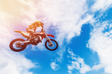 racer on a motorcycle participates in motocross in flight, jumps and takes off on a springboard...