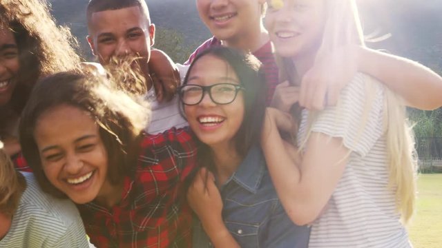 Teenage school friends smiling to camera outdoors, close up