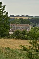 Fototapeta na wymiar L'église médiévale romane et les toits de tourelles du château de Champagne émergeant de la nature du Périgord Vert 