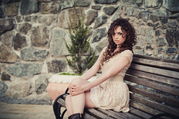 Brown-eyed brunette girl sitting on a bench