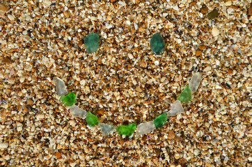 symbol of smile of glass pebbles on the sand