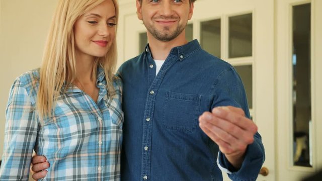 Young couple in love getting a key to their new home from on the door background of new house.