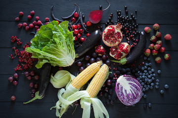 Collection of fresh purple, red and green fruit and vegetables on the black wooden table