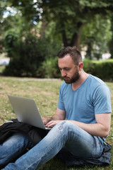 young man working on laptop in nature 