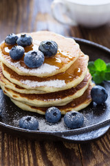Blueberry buttermilk pancakes with maple syrup on rustic table