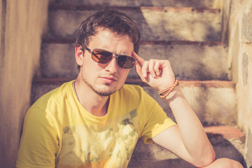Junger Mann sitzt auf Steintreppe, cooler Blick